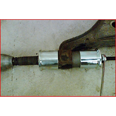 Eine Nahaufnahme des demontierten Teils einer Fahrzeugaufhängung, die durch einen neuen Zylinder ersetzt wird. Ein Schraubenschlüssel wird verwendet.